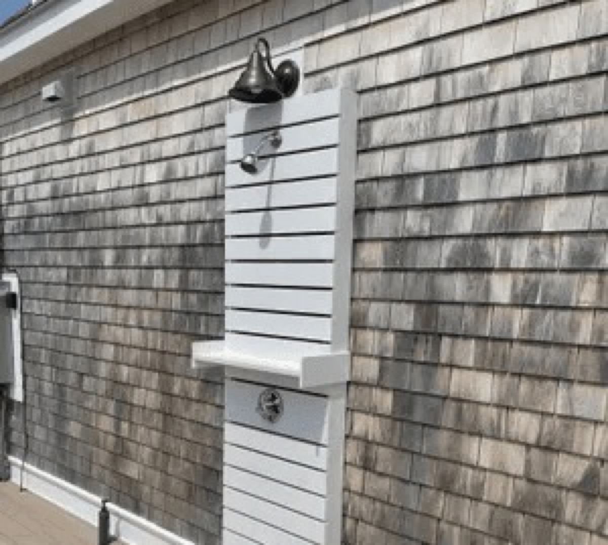 Detail shot of natural cedar shingle siding with white trim and an exterior light fixture on a Biviano modular build