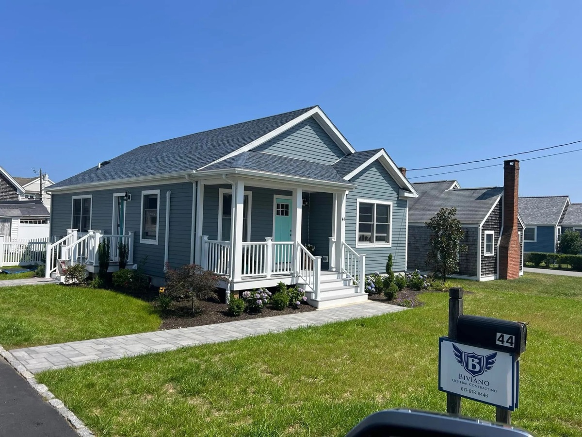 Completed Biviano modular spec home in Marshfield MA — blue-gray clapboard siding, white trim, mint front door, manicured landscaping